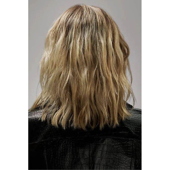 Woman with wavy blonde hair using Oribe Flash Form Finishing Spray Wax for a texturized look
