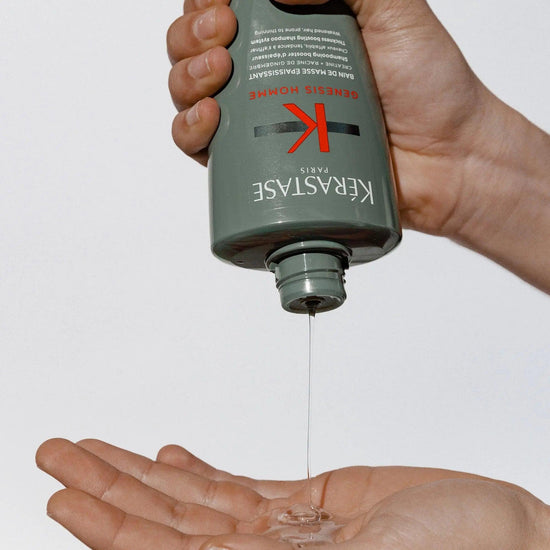 Person dispensing Kérastase Genesis Homme Bain De Masse Épaississant Shampoo onto hand